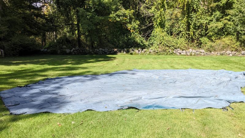 Laying a pool cover on grass to check for holes